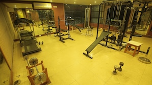 A gym with various exercise equipment, including treadmills, weight machines, and dumbbells. - Hotel Vijayetha (Nagercoil)