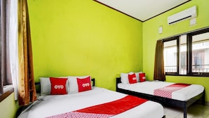 Une chambre d’hôtel avec deux lits, chacun doté de draps et d’oreillers rouges et blancs, une fenêtre avec des rideaux et un climatiseur fixé au mur.