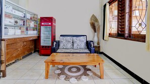 Un salon comprenant un canapé, une table basse, une cabine téléphonique rouge et une vitrine en verre contenant divers objets.