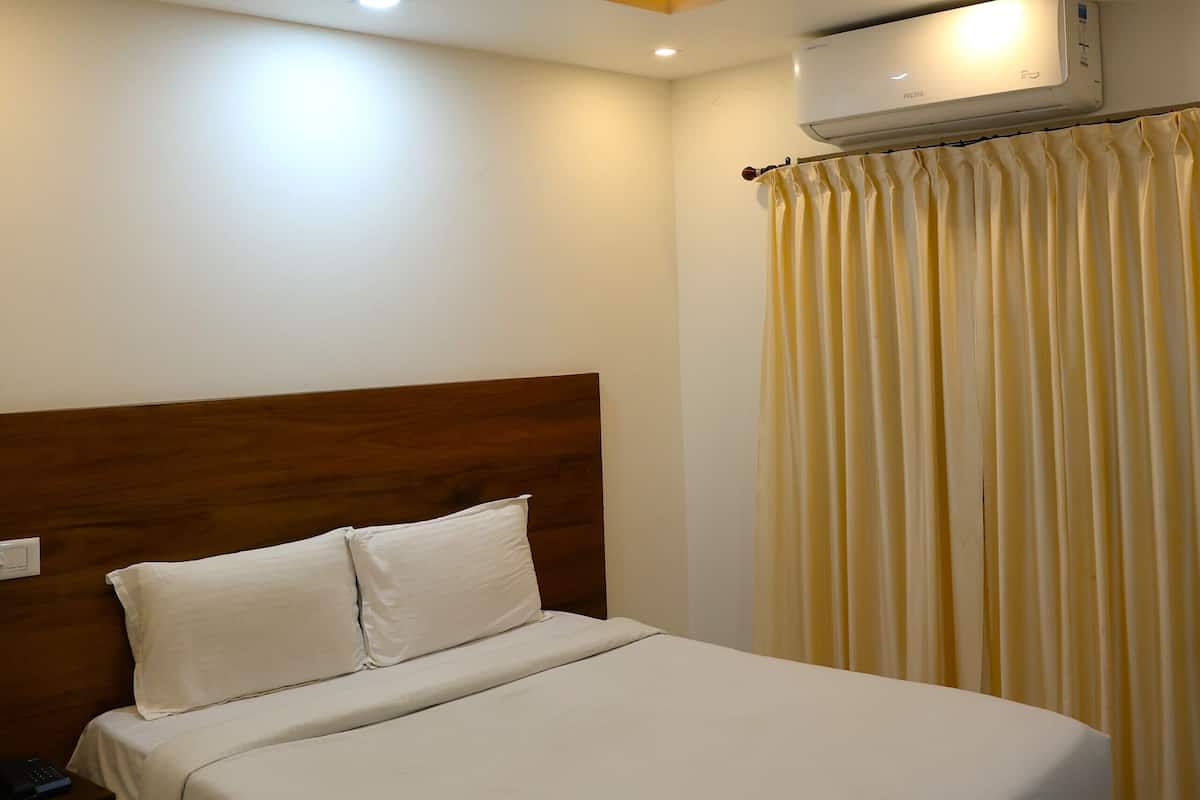 Un dormitorio con cama, ventilador de techo, aire acondicionado y cortina.