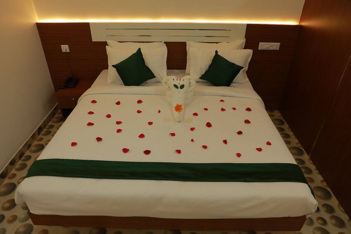 Una cama bien hecha con una colcha verde, almohadas blancas y un adorno decorativo.