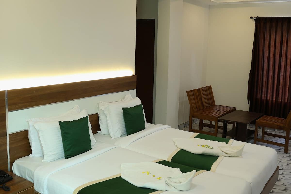 Habitación de hotel con una cama grande, un escritorio, dos sillas, un ventilador de techo y un suelo estampado.