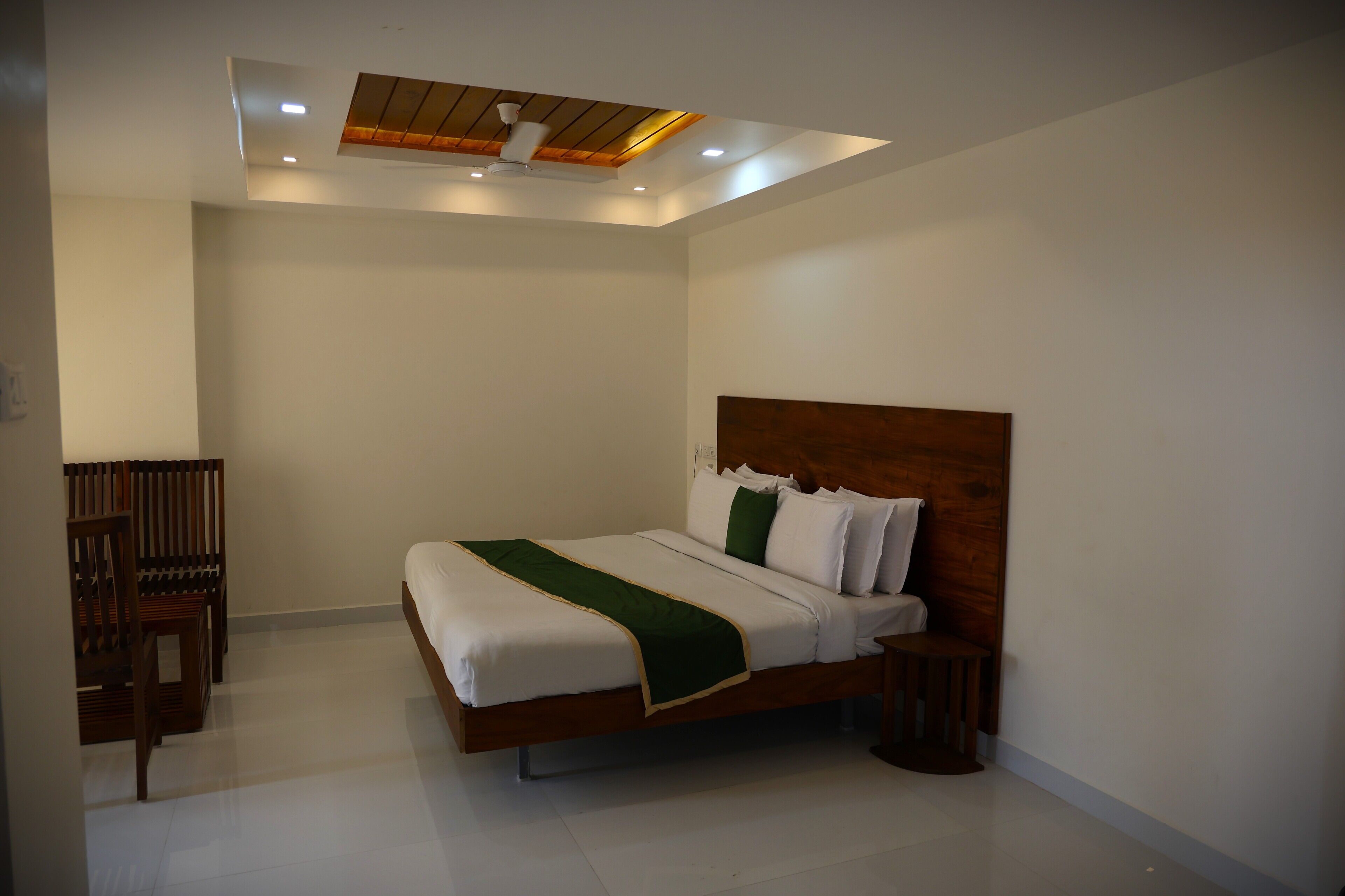 Een slaapkamer met een bed, een houten hoofdbord, een nachtkastje en een stoel.