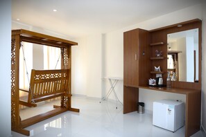 Una habitación con un banco de madera, un refrigerador blanco pequeño y un mueble de madera con estantes.