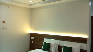 Habitación de hotel con cama, ventilador de techo, iluminación empotrada y techo de madera.