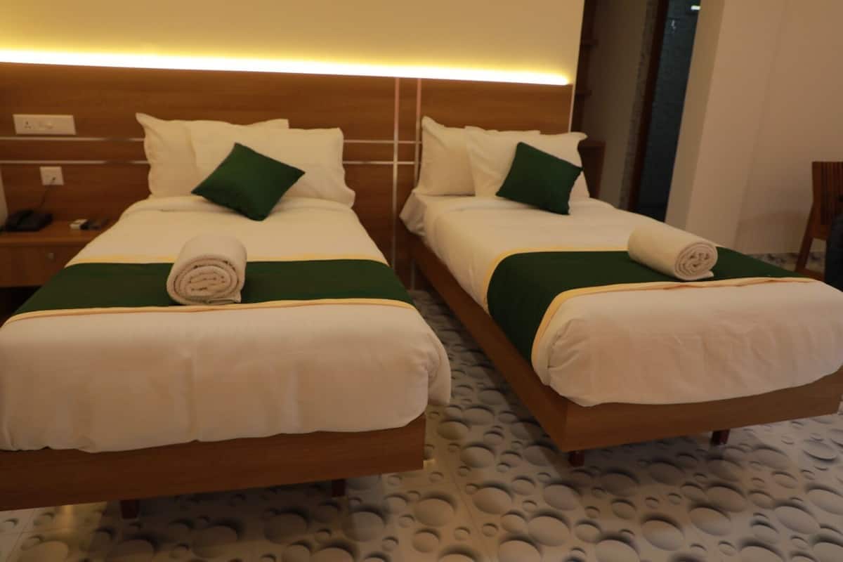 Dos camas individuales con ropa de cama verde y blanca, un cabecero de madera y un suelo estampado.