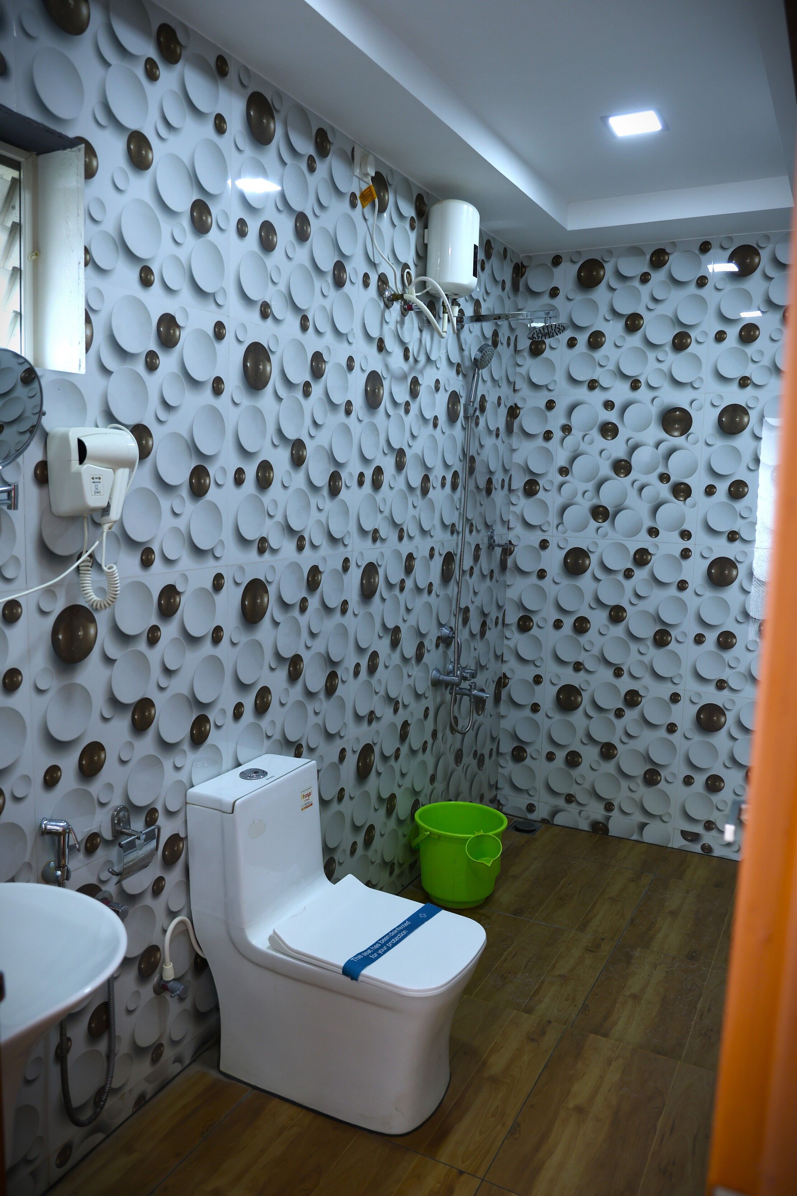 A bathroom with a toilet, sink, shower, and a wall with circular patterns.