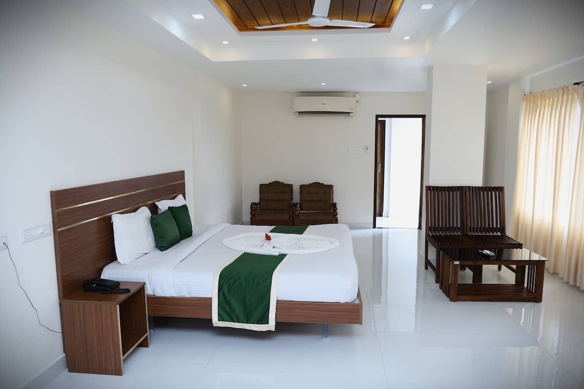 Una habitación de hotel con cama, mesita de noche, silla y aire acondicionado.