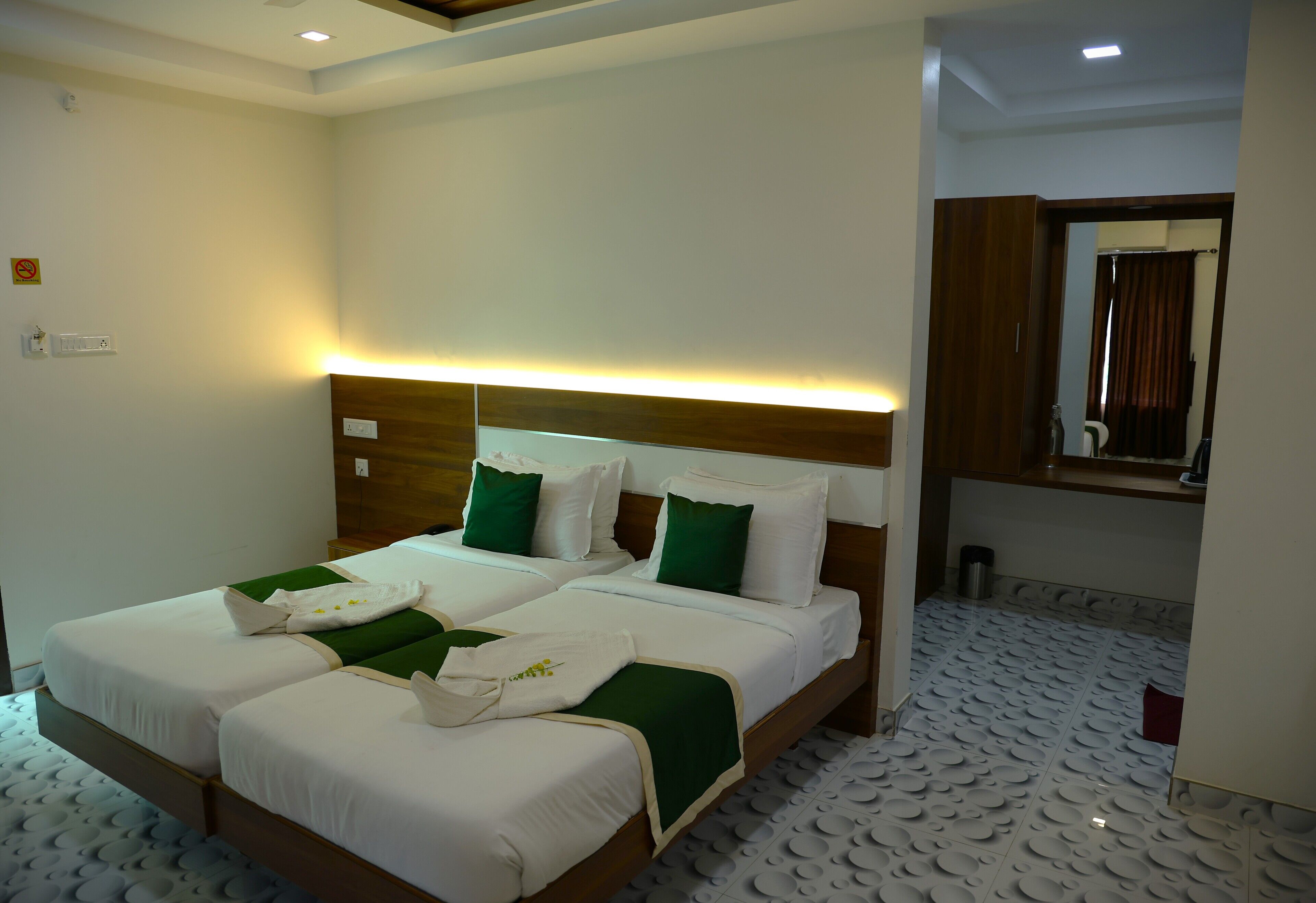 Een hotelkamer met een tweepersoonsbed, een hoofdeinde met geïntegreerde verlichting, een spiegel en een vloer met een patroon.