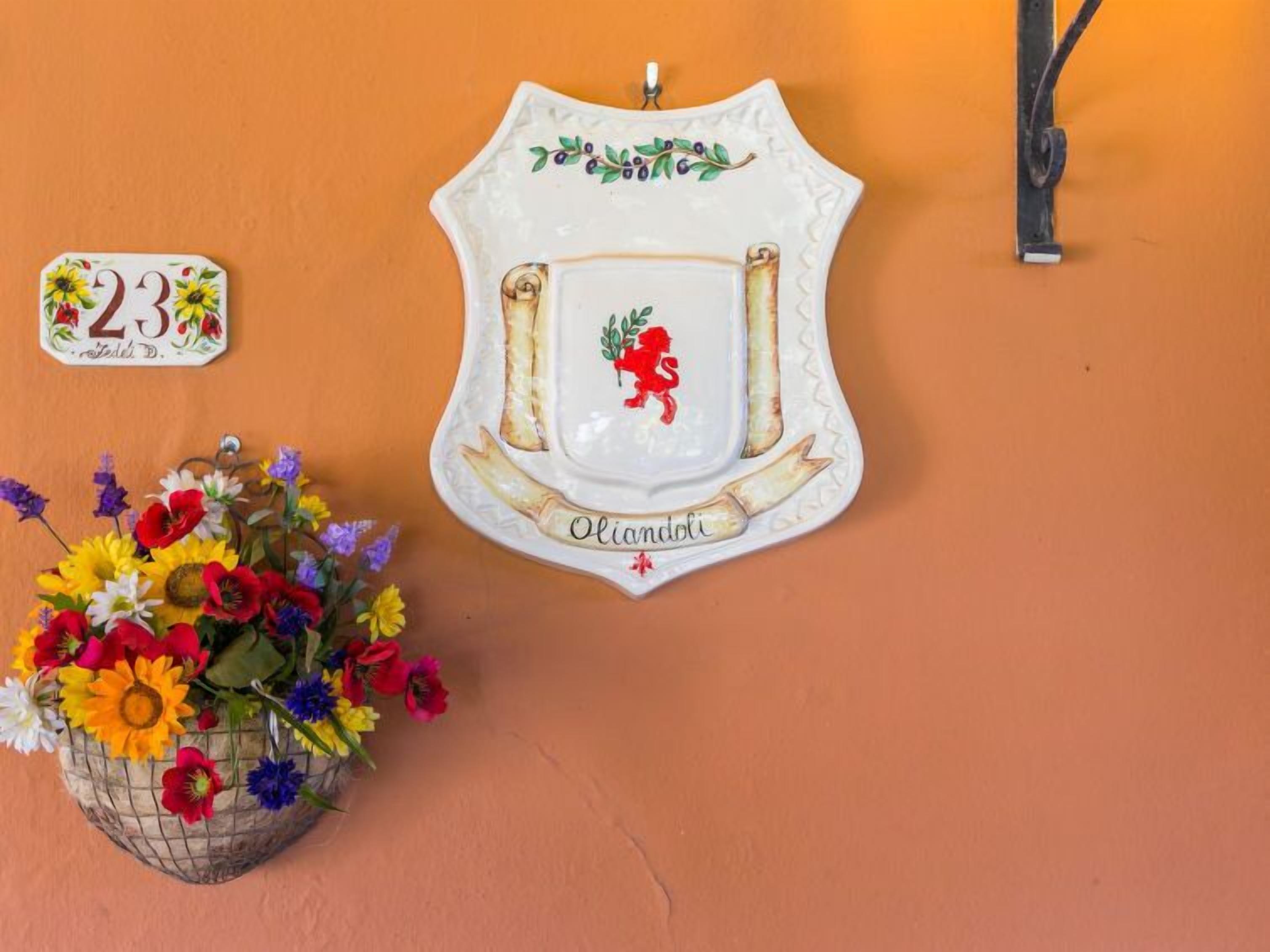 Une assiette décorative ornée d’un lion rouge et portant l’inscription « Oliandoli », accrochée à un mur.