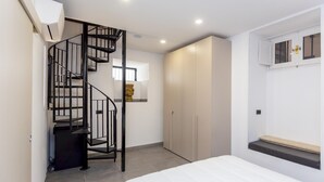 Un dormitorio con cama, escaleras, armario y una ventana pequeña.