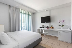 Une chambre d’hôtel moderne équipée d’un lit, d’un bureau, d’une télévision et d’une petite plante.