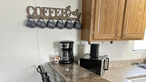 Una cocina con armarios de madera, encimera de granito y un letrero que indica barra de café.