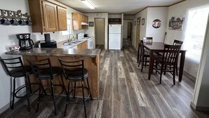 Una cocina compacta con barra, armarios de madera y una mesa de comedor con sillas.
