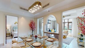 A spacious dining area with a glass table set for six, surrounded by white upholstered chairs with gold accents. - Charming 2 Bed l Old Town Dubai l Memorable stay (Downtown Dubai)