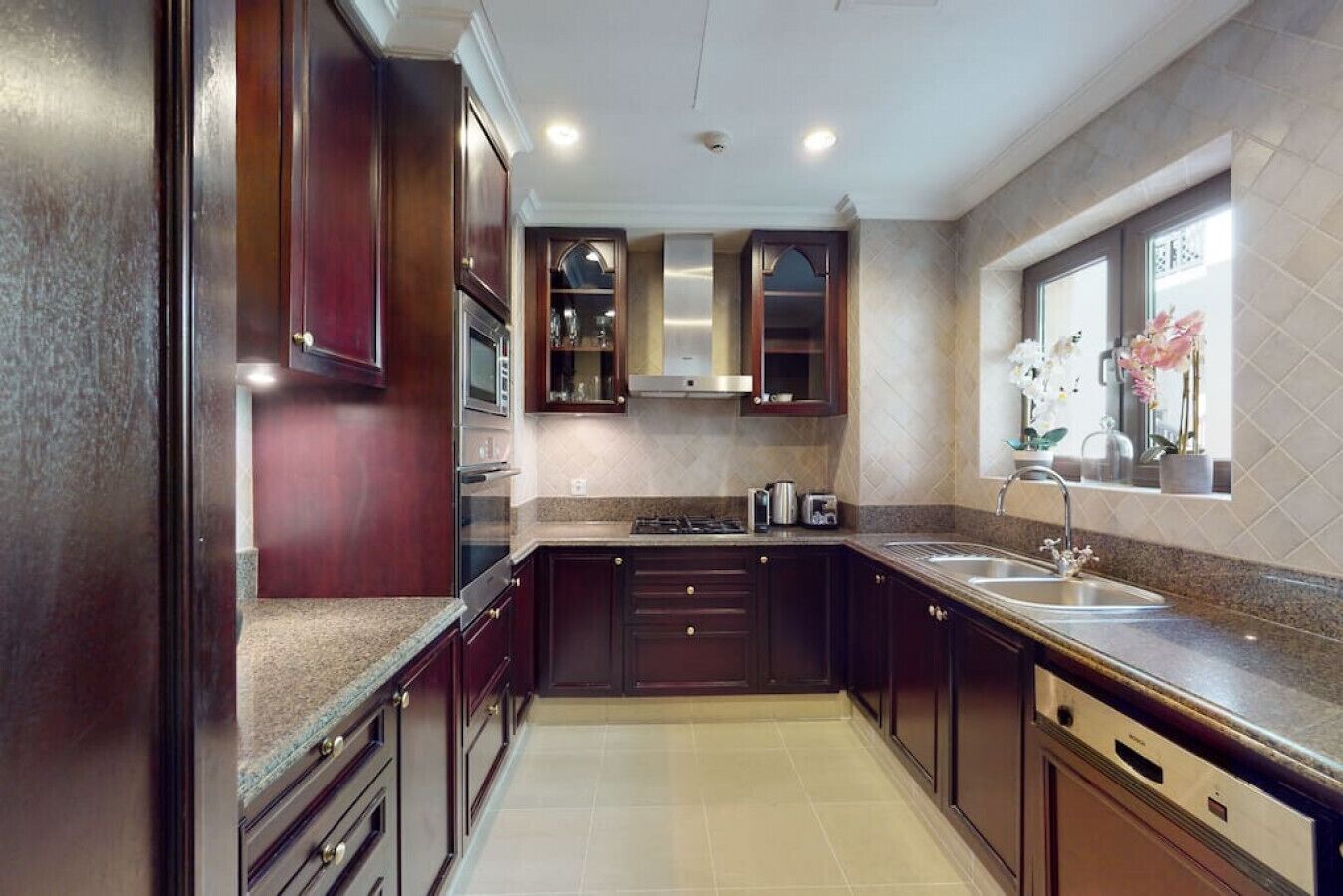 Una cocina moderna con armarios de madera oscura, electrodomésticos de acero inoxidable y encimera de granito.