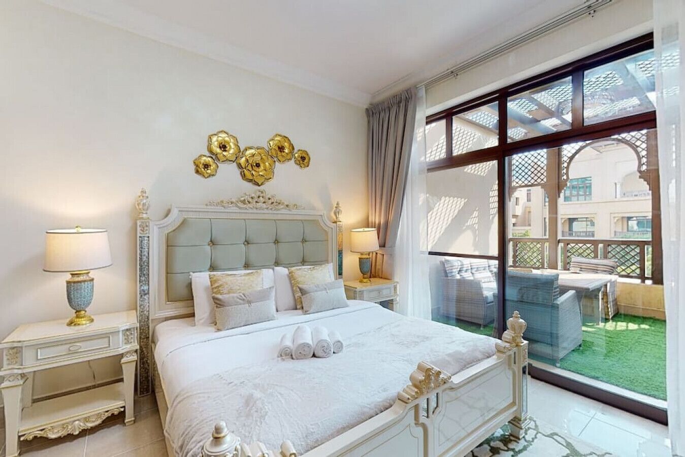 A luxurious bedroom with a large bed, ornate headboard, and decorative wall art.