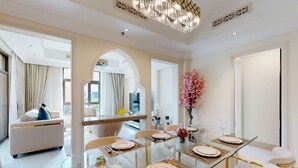 A spacious dining area with a glass table set for six, surrounded by white sofas and a large mirror. - Charming 2 Bed l Old Town Dubai l Memorable stay (Downtown Dubai)