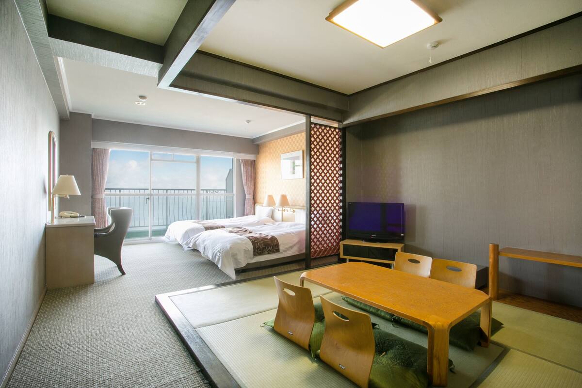 A hotel room with a bed, a desk, a television, and a dining table.