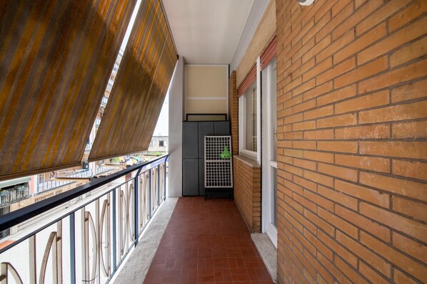 Un couloir étroit, doté d’un sol carrelé, d’une rambarde en métal et d’un mur en briques.