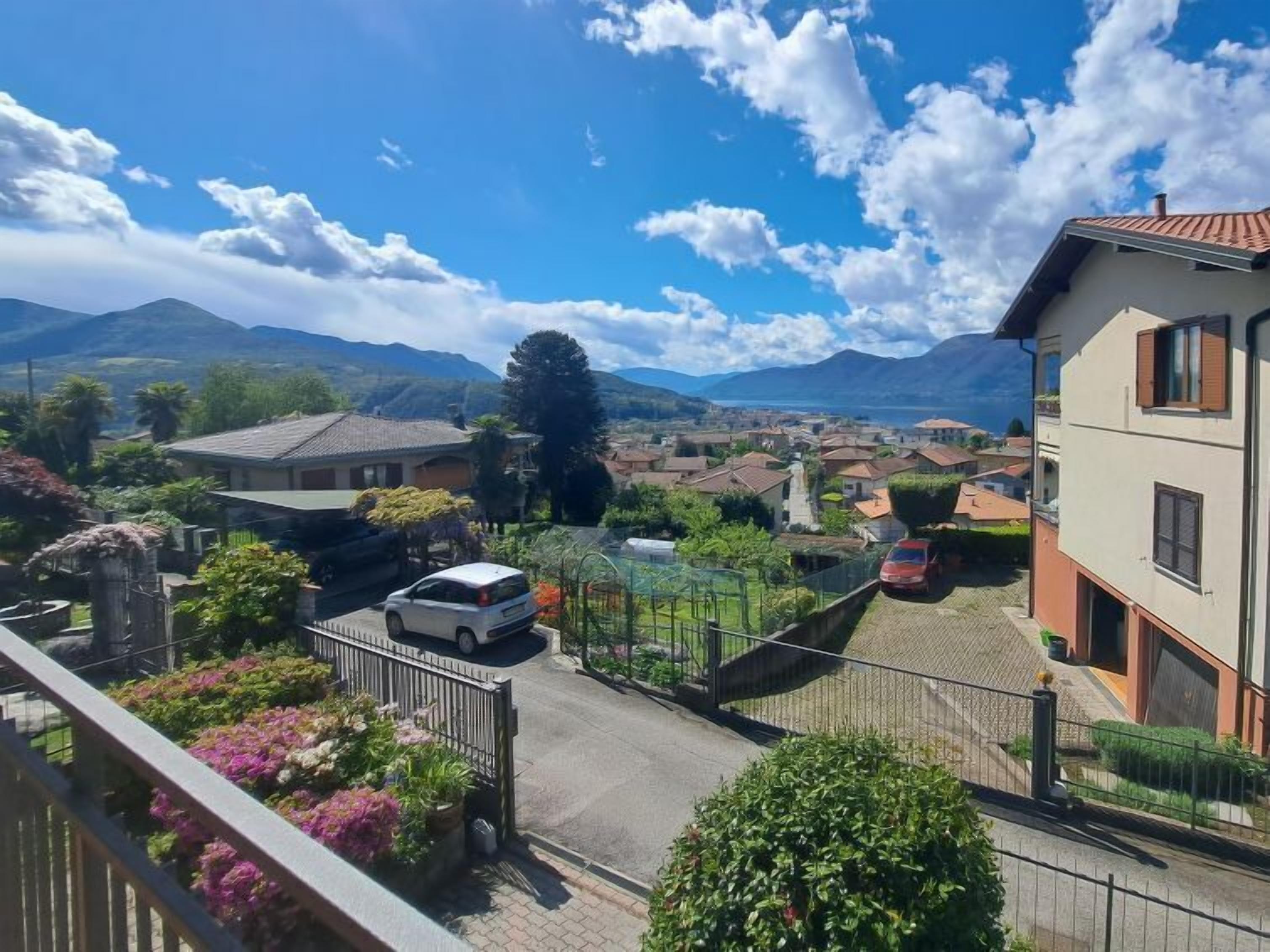 A residential area with houses, a white car, and mountains in the background.