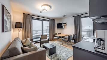 Une chambre d’hôtel moderne équipée d’un canapé, d’une table basse, d’une table à manger, de chaises et d’un coin cuisine.