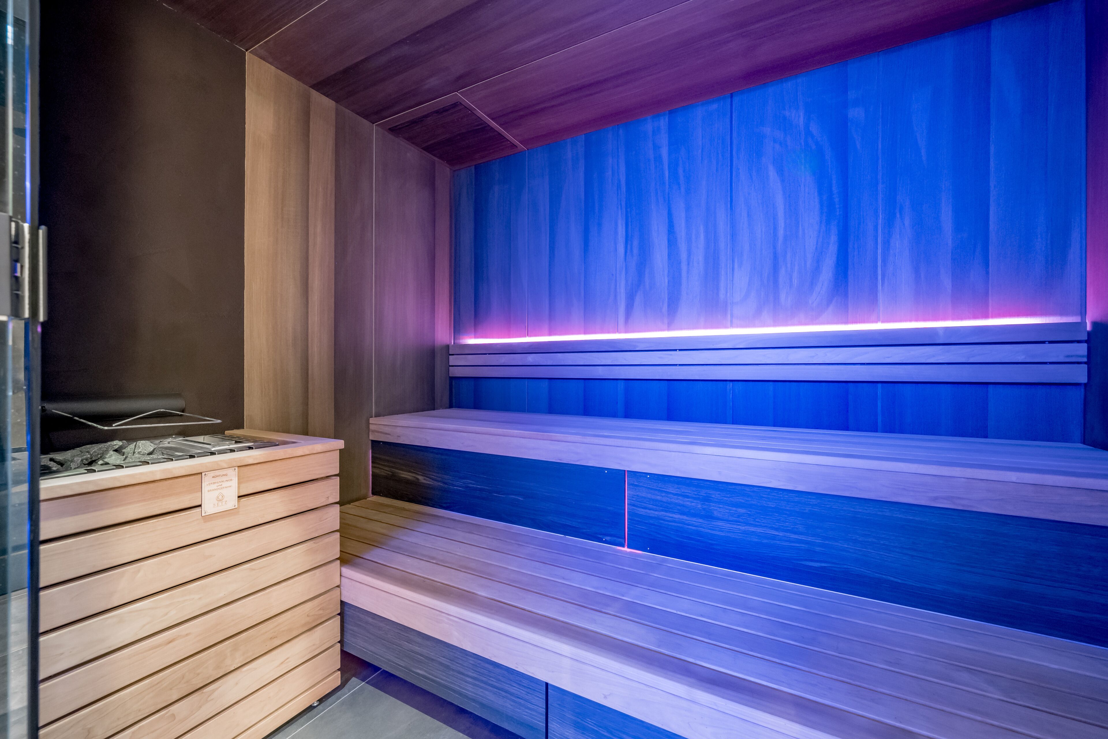 Eine Sauna mit Holzbänken und einer blauen Wand.