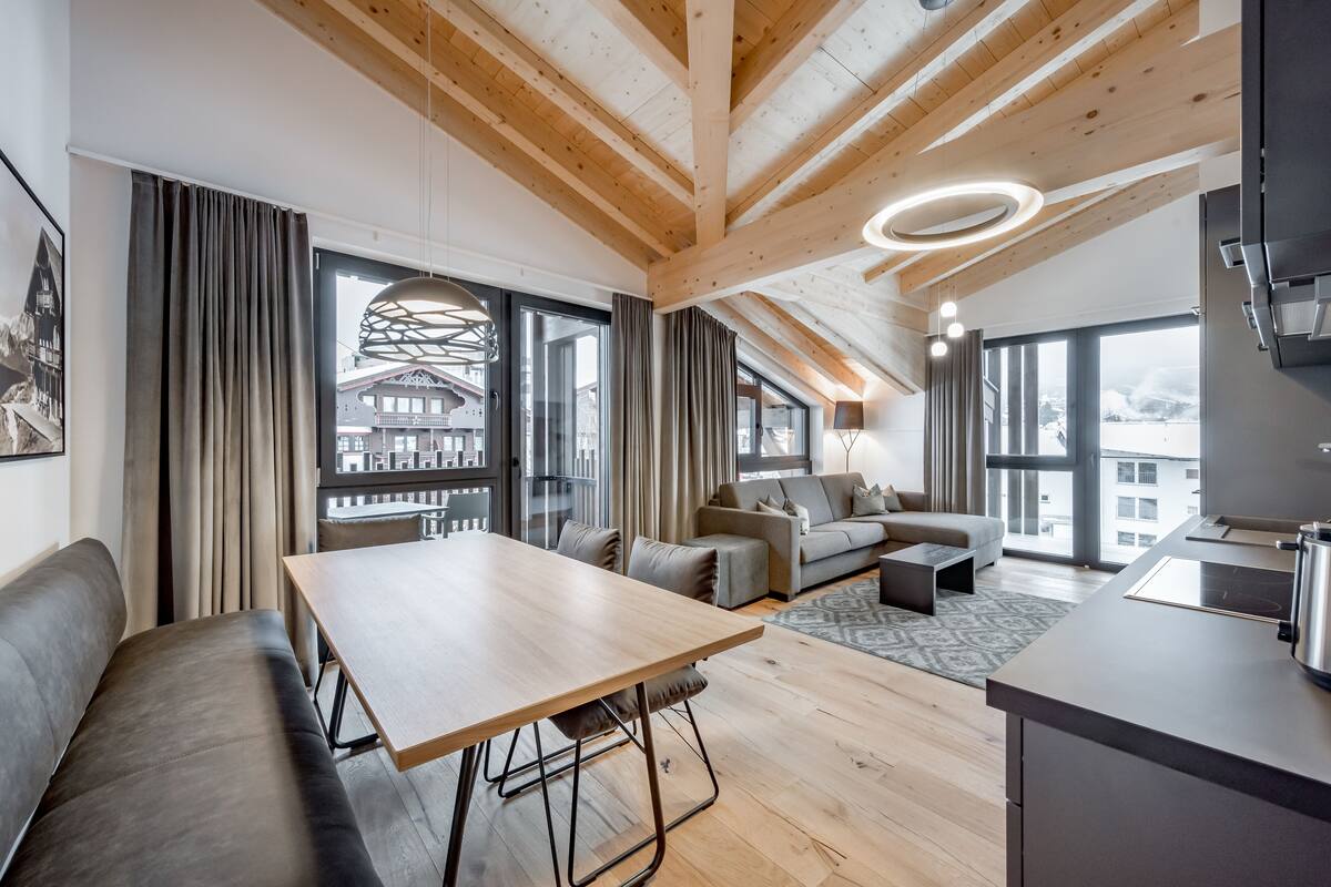 A modern interior with a wooden ceiling, a dining area, a sofa, and a kitchen.