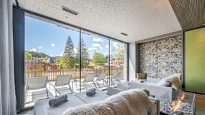 A modern room with a glass wall, a fireplace, and a view of a mountain. - Summit Seefeld (Seefeld in Tirol)