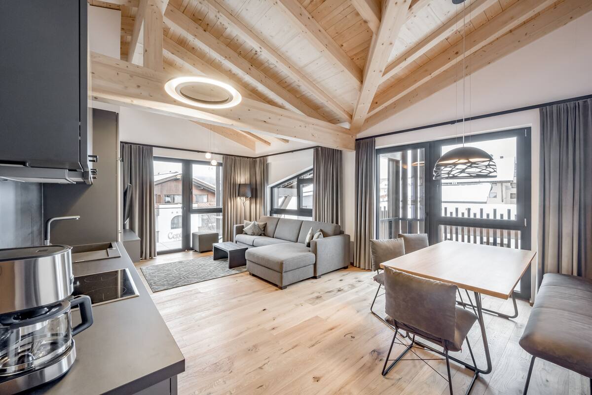 A modern living room with a sofa, a dining table, and a coffee maker.