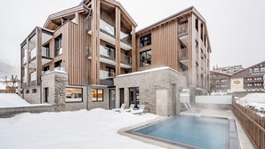 A modern multi-story building with a pool area, stone accents, and wooden paneling.