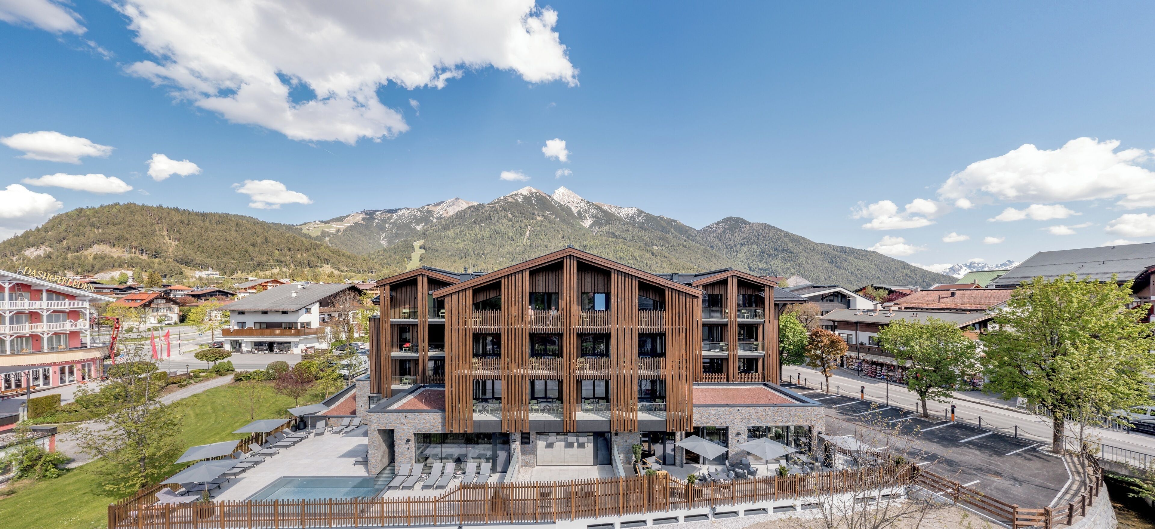 A modern hotel with a central courtyard, surrounded by mountains and other buildings.