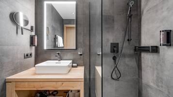 Ein modernes Badezimmer mit einem großen Spiegel, einem Waschbecken, einer Dusche und einem Schminktisch mit Handtuchhalter.