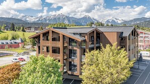 A modern building with a wooden facade, a parking lot, and a mountainous backdrop.