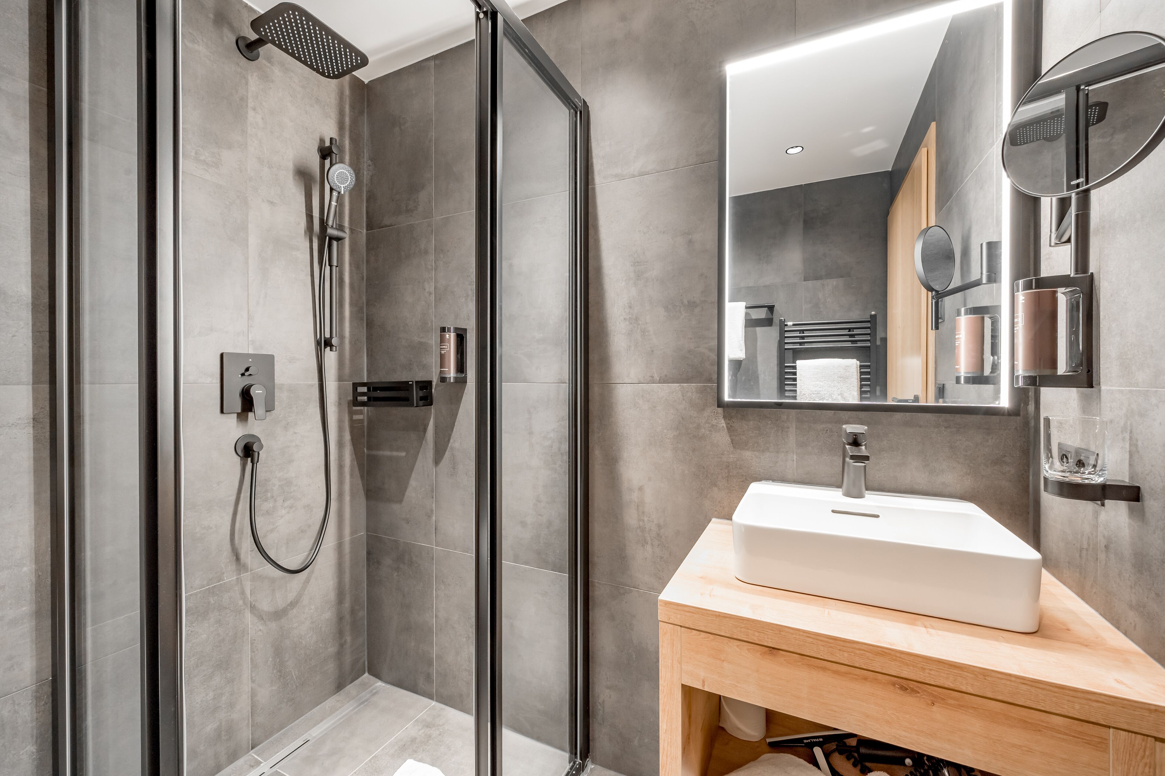 Une salle de bain moderne avec une douche à parois de verre, un meuble-lavabo en bois et un grand miroir.