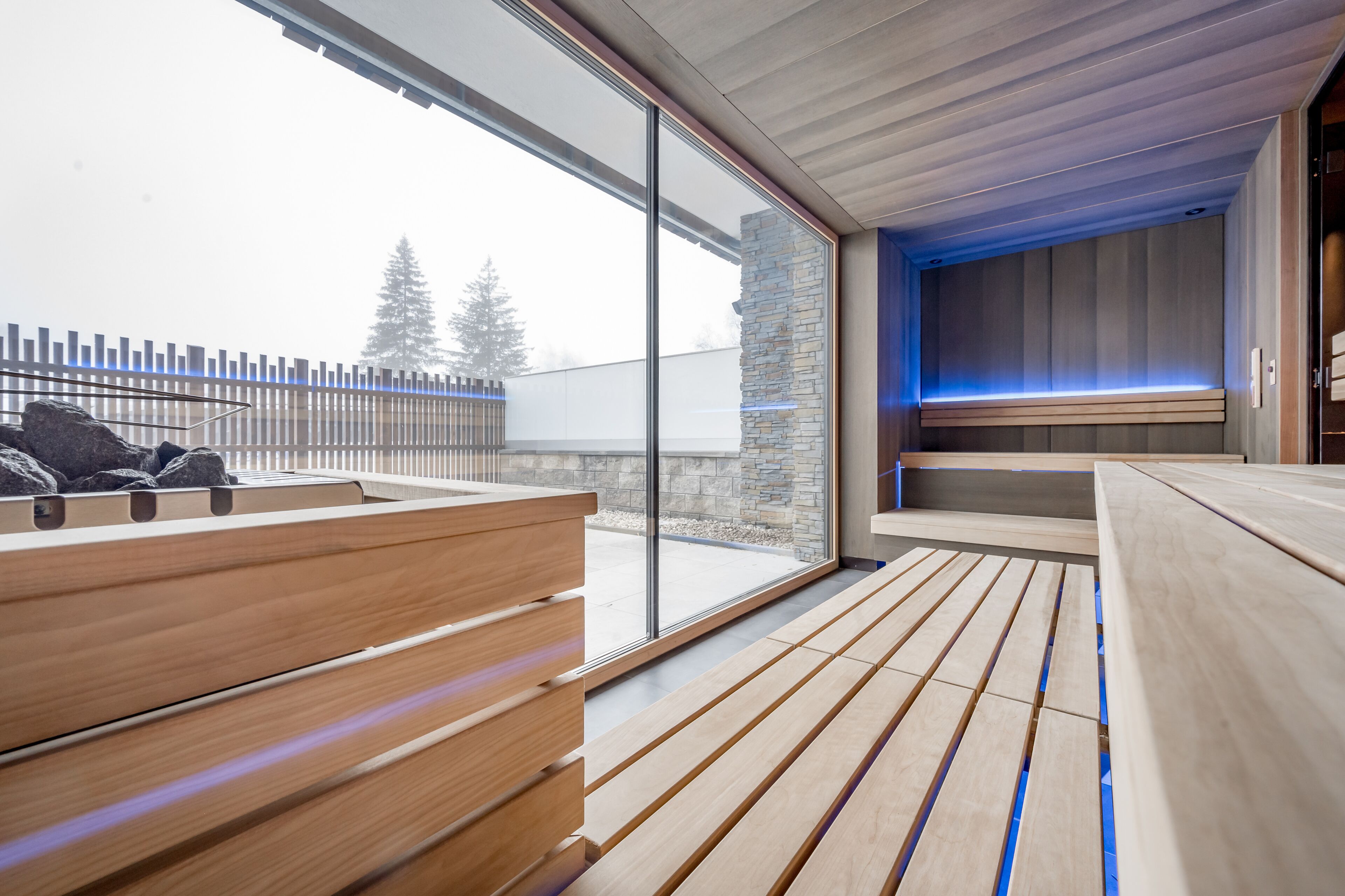 A modern spa area with wooden benches and a stone wall.