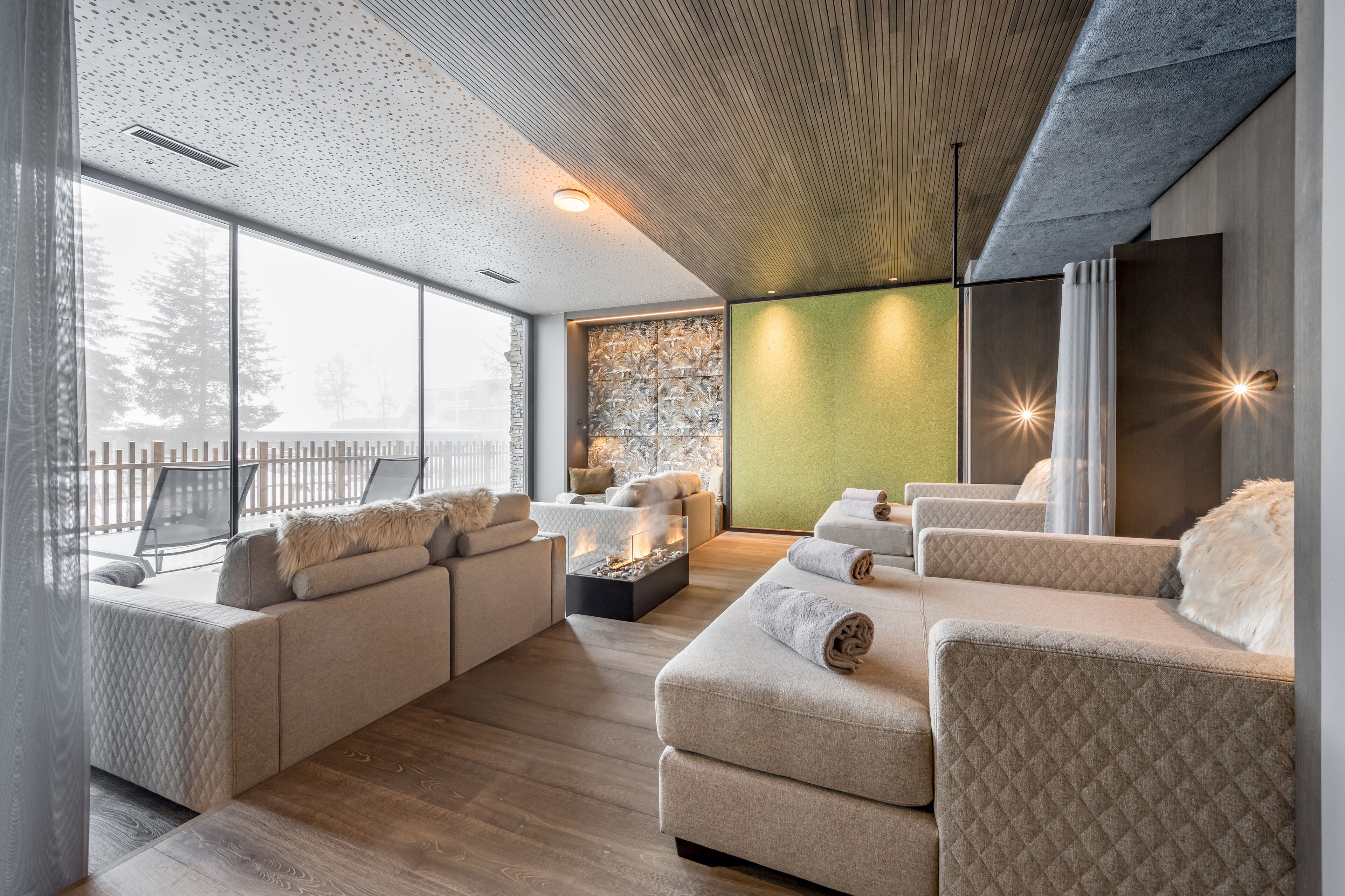 Een moderne woonkamer met een groot raam, een open haard en een groene accentmuur.