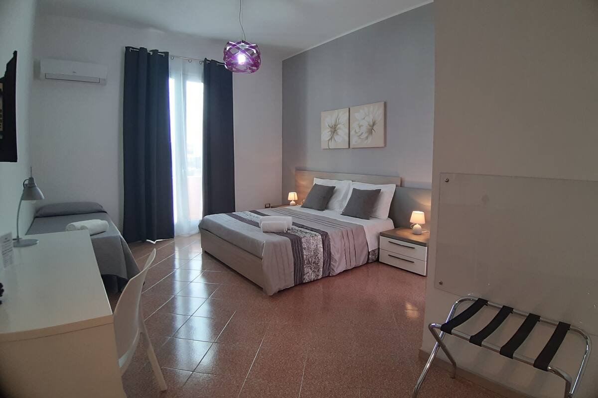 Une chambre à coucher moderne avec un lit, des tables de chevet, un bureau et une chaise.