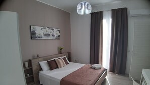 A neatly arranged bedroom with a bed, bedside tables, a wall-mounted artwork, and a window with curtains. - Costa Sicula (Avola)