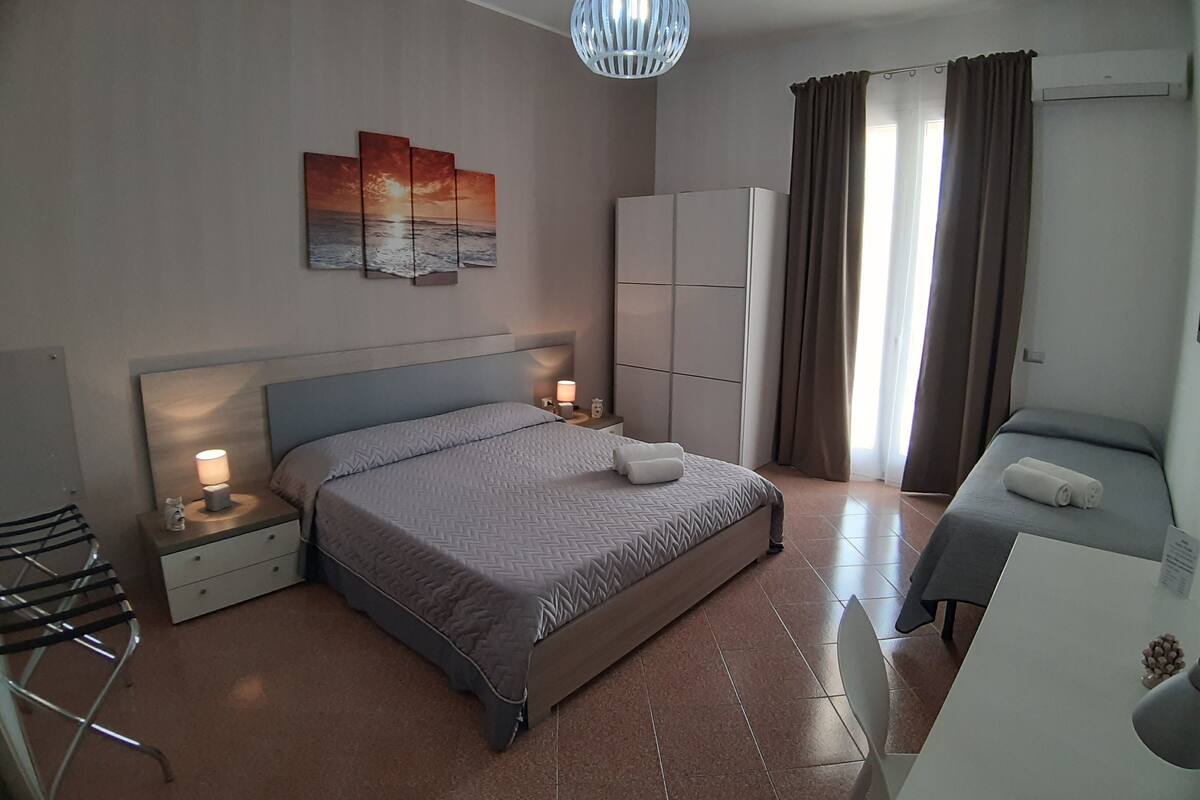 Une chambre à coucher moderne avec un grand lit, des tables de chevet avec des lampes, un bureau et une armoire.
