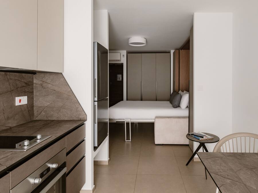 A compact living space with a kitchenette, a bed, and a small dining area.