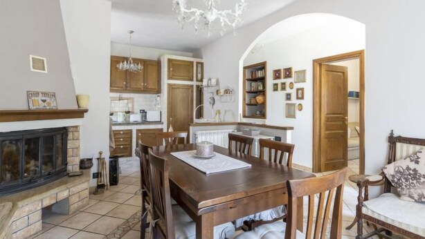 A dining room with a wooden table and chairs, a chandelier, and a fireplace. - Vacation home Anna by Interhome (Ville San Pietro)