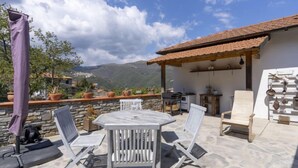 A stone patio with a table and chairs, a pergola, and a view of the mountains. - Vacation home Anna by Interhome (Ville San Pietro)