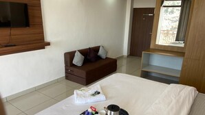 A hotel room with a bed, a TV mounted on the wall, a sofa, a window, and a tray with breakfast items. - The Bliss Dhanaulti (Dehradun)