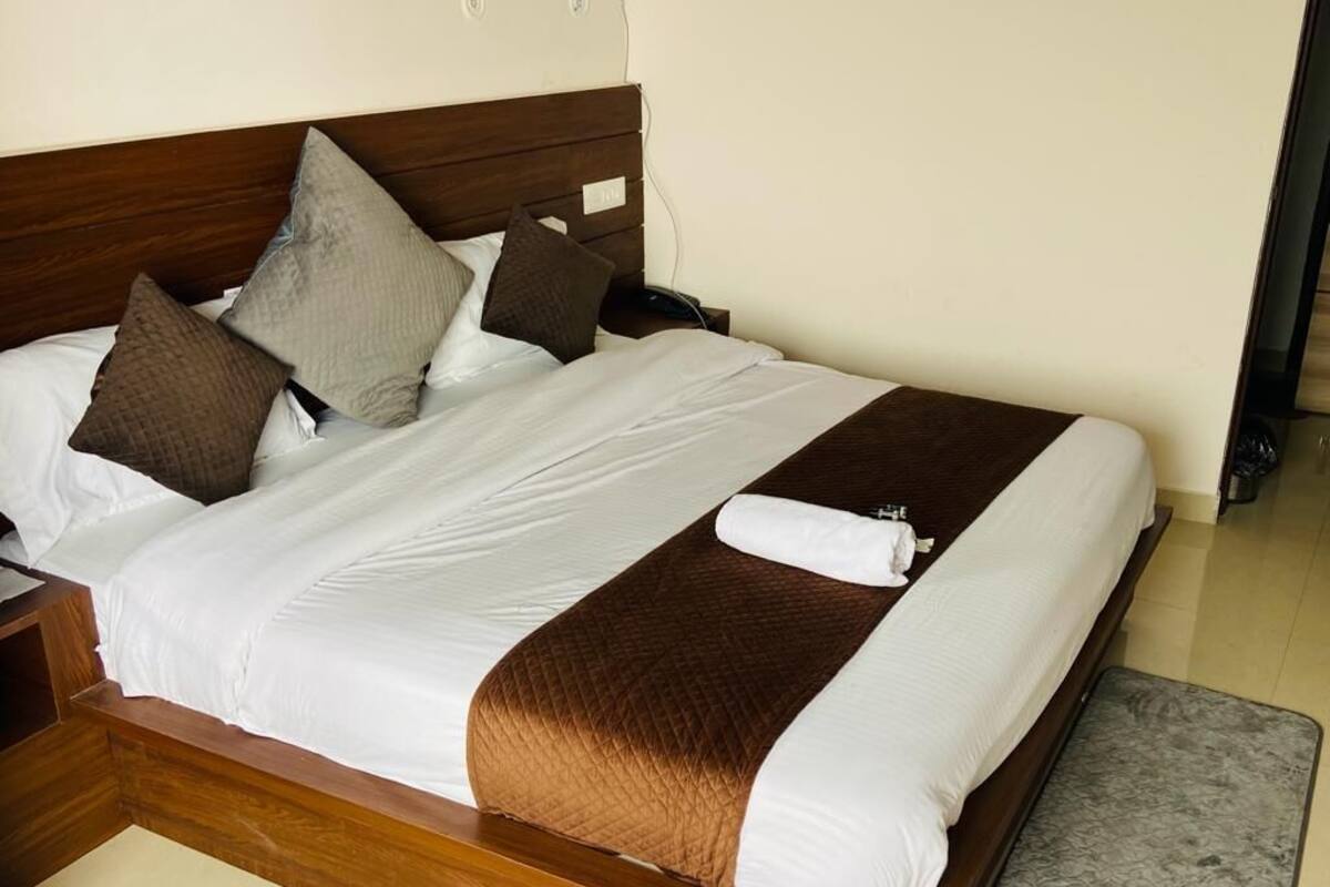 A neatly made bed with a wooden headboard, white and brown bedding, and a gray rug.