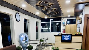 Zona de recepción con mostrador de recepción, un reloj, un sofá y una mesa de registro.