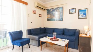Een woonkamer met een blauwe bank, een blauwe fauteuil, een klein houten tafeltje en een kast.