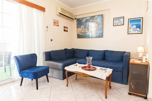 Una sala de estar con un sofá azul, un sillón azul, una mesita de madera y un aparador.