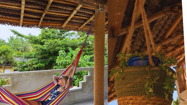 A hammock under a wooden roof, a concrete wall, and a hanging basket with plants. - Sri Lanka Surf Villa (Koggala)