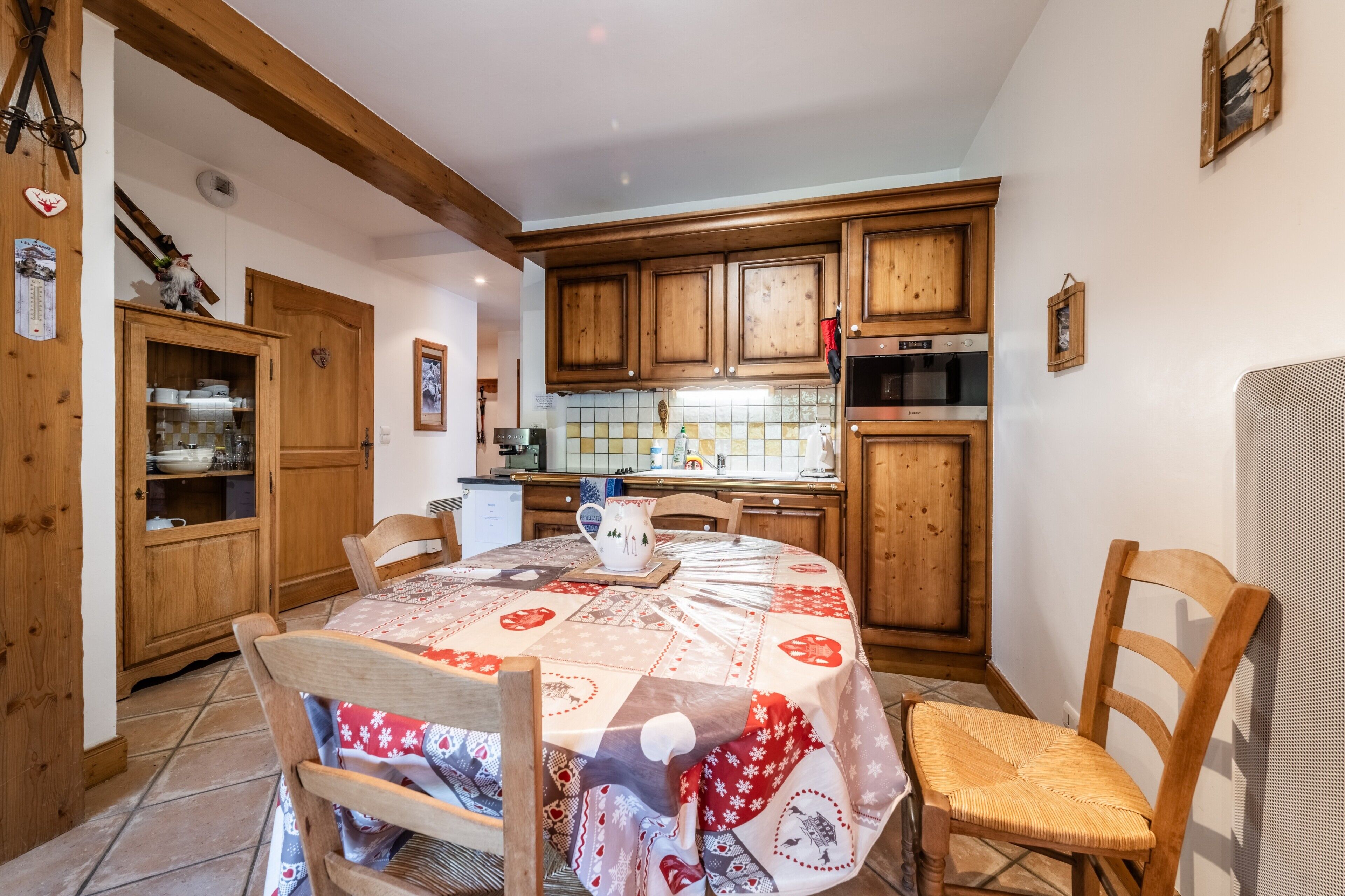 Una cucina accogliente con mobili in legno, un tavolo da pranzo con tovaglia fantasia e una sedia.